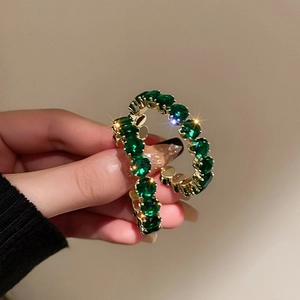 Détail macro de boucles d'oreilles dorées style français avec cristaux vert émeraude en C