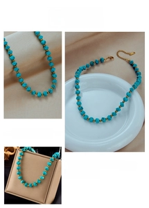 Dettaglio delle perline turchesi e perle dorate con chiusura a moschettone sulla collana