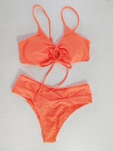 Detailed flat lay of a coral orange halter bikini set with ring detail and side pleats