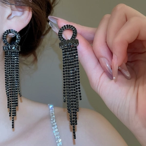 Detailed close-up of geometric black rhinestone tassel earrings worn on ear model