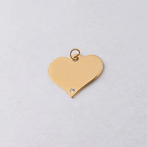 Macro detail of a gold heart pendant with a sparkling crystal stone and jump ring