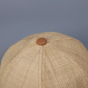 Close-up of natural straw weave texture and brown leather button on the baseball cap