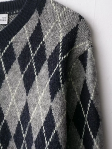 Detailed close-up of dark blue and grey argyle knit sweater showing texture and neckline