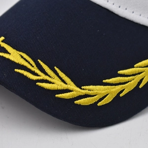 Close-up of gold embroidered leaves on navy blue cotton peak of the captain baseball hat