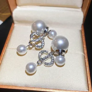 Elegant silver-tone double pearl earrings with sparkling crystal-set CD logo in jewelry box