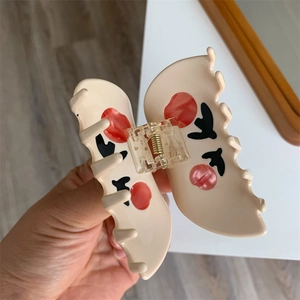 Detailed close-up of butterfly hair claw with beige wings and abstract red patterns