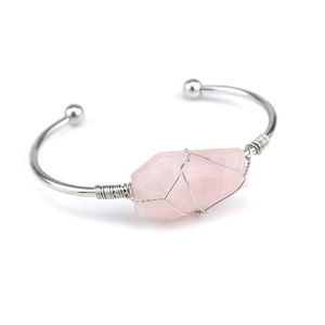 Detail view of pink raw crystal wrapped in silver copper wire on an open cuff bracelet