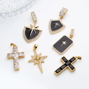 Golden cross and shield pendants with black enamel and zircon inlay on white background