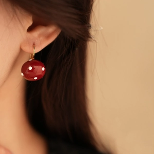 Close-up of a French vintage red mushroom earring with white polka dots on model ear