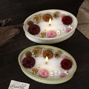 Striped oval scented candle molds with dried flowers and wooden wicks on dark wood background
