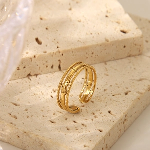 Macro detail of vintage gold crown ring showing hollow pattern on travertine surface