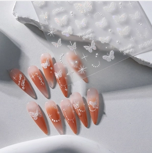 Close-up of butterfly nail stickers with white 3D beads on orange ombre stiletto nails