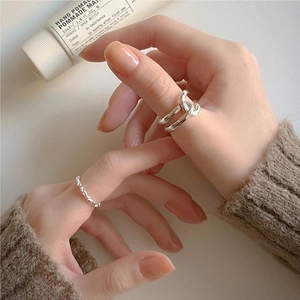 Close-up of model wearing silver double-layered crisscross and wavy textured rings