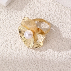 Macro detail of golden flower ring with pearl center and textured metal petals