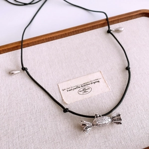 Detail of candy-shaped vintage silver pendant with baroque engraving on black leather cord