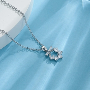 Silver bowtie flower pendant necklace with clear zircon stones on a water ripple background