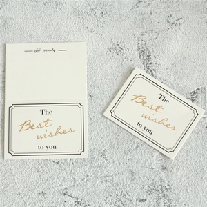 Close-up of elegant cream-colored greeting cards with gold foil lettering on stone surface