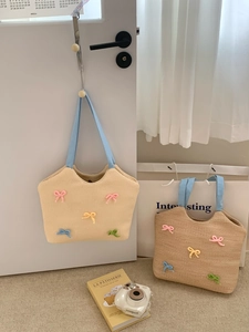 Detail of hand-woven straw tote bag with colorful 3D crochet bows and blue canvas straps