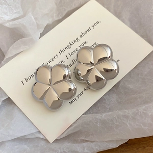 Macro shot of silver flower earrings with metallic mirror finish on a white display card