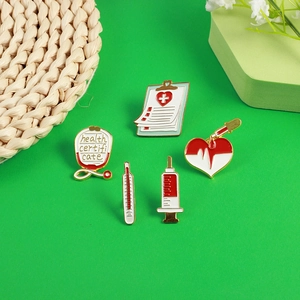 Enamel medical brooch set featuring stethoscope, syringe, and thermometer on green background