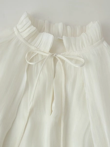 Close-up of elegant ruffled high neck and delicate drawstring bow on white chiffon dress