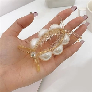 Détail d'une grande pince à cheveux avec perles blanches élégantes et finition dorée