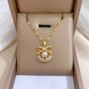 Elegant gold bow necklace with white pearl and sparkling crystals in a premium gift box
