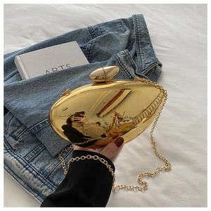 Detailed view of a mango-shaped gold acrylic clutch bag with a metallic chain strap