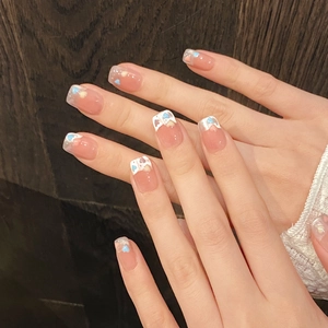 Detailed view of square oval press-on nails with French tips and colorful heart glitter