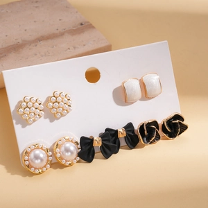 Macro shot of 10-piece pearl bow flower earring set on card with stone texture