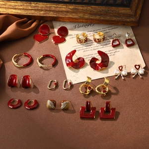 Close-up of vintage gold and red enamel earrings with pearls on a rustic fabric background