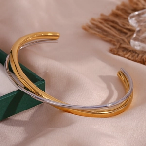 Detail of minimalist 18K gold and silver layered open bangles on silk background