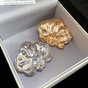 Close-up of orchid flower brooches in gold and silver metal with textured finish