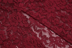 Dettaglio macro del pizzo floreale rosso vino con delicati ricami traforati