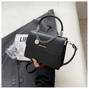 Close-up of black crossbody bag with silver chain detail and fashion lettering