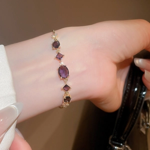 Detail of adjustable gold bracelet with purple zircon butterfly and oval gemstones