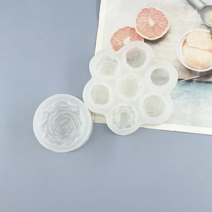 Detail of white silicone rose and 6-cavity flower molds on a gray styled background