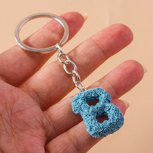 Close-up of blue resin letter B keychain with detailed rose floral relief pattern