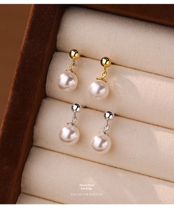 Detail of gold and silver S925 sterling silver drop earrings with white pearls in a jewelry box