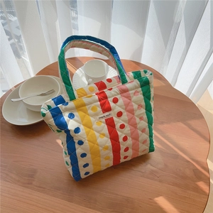 Détail d'un sac à main matelassé à rayures avec étiquette Simple Wish sur bois