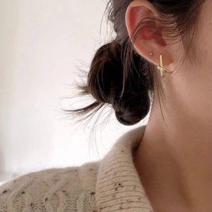 Minimalist gold geometric knot earrings worn by a model in a close-up profile shot