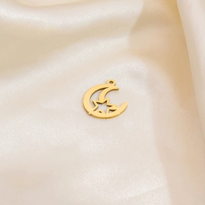 Detailed close-up of a hollow crescent moon and star pendant in a gold finish on silk