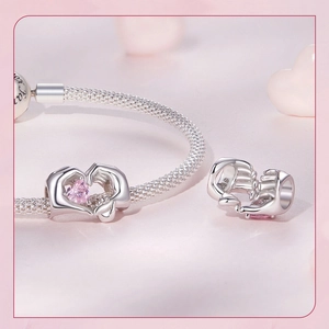Macro detail of S925 silver heart charm with pink gemstone on a mesh bracelet