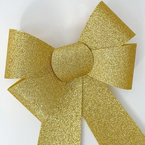 Macro detail of golden glitter bow decoration with textured sparkling finish for Christmas