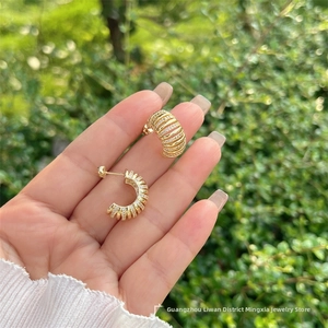 Détail de boucles d'oreilles créoles dorées 18k à bandes multiples serties de zircones