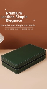 Deep green leather watch travel case with white stitching and zipper on a stylish desk