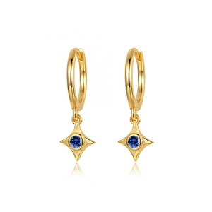 Detailed shot of gold hoop earrings with star pendants and central blue zircon