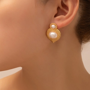 Macro shot of vintage gold flower earrings with pearl inlays worn on a model's ear