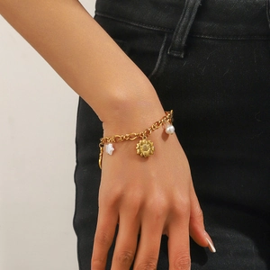 Detail of a gold-plated flower bracelet with pearl stars on a woman's wrist