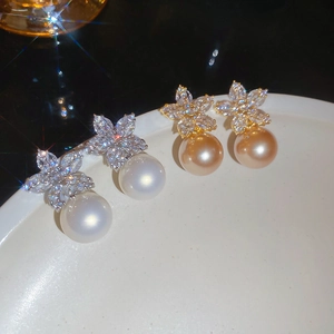 Detailed macro view of white and champagne pearl earrings with zircon flower settings